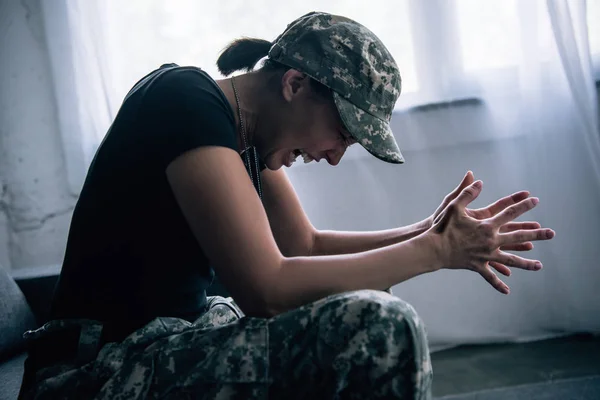 Mulher deprimida em uniforme militar gritando em casa — Fotografia de Stock