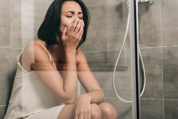 Atractiva mujer molesta sentada y llorando en la ducha en casa - foto de stock