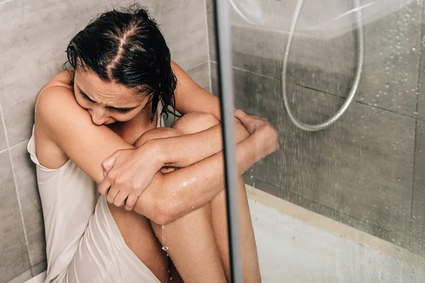 Mujer preocupada sola sentada en la ducha en casa - foto de stock