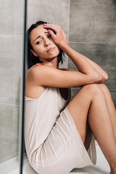 Mujer deprimida sola sentada en la ducha y llorando en casa - foto de stock