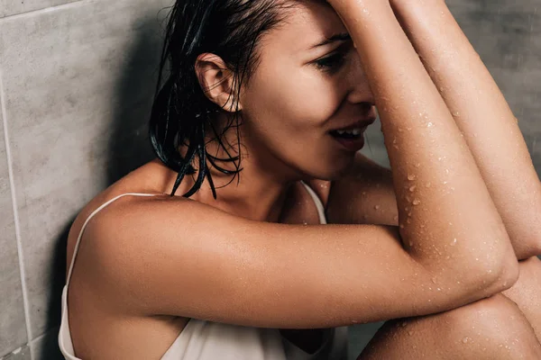 Mujer deprimida sola sentada en la ducha y llorando en casa - foto de stock