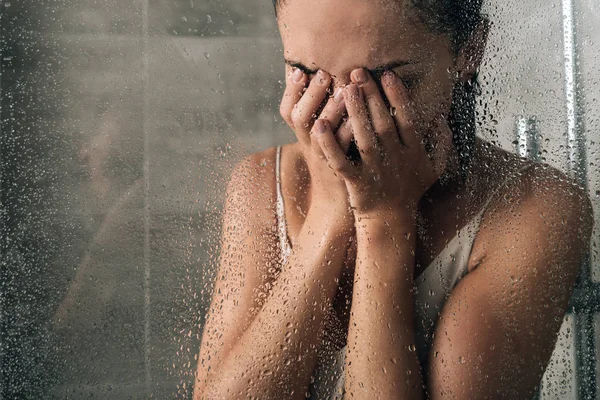 Upset sad woman covering face and crying in shower at home — Stock Photo