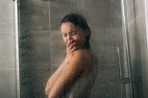 Beautiful sad woman covering face and crying in shower at home — Stock Photo