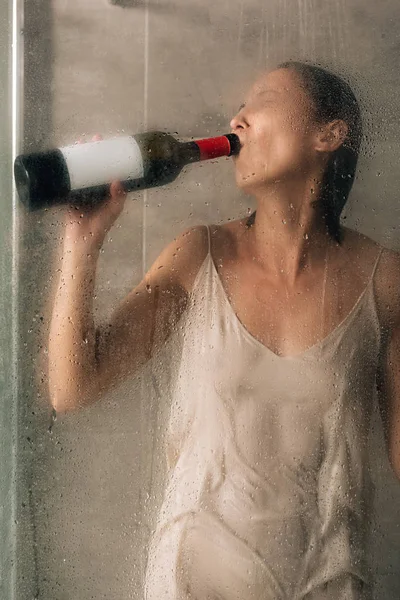 Einsame depressive Frau unter der Dusche trinkt zu Hause Wein — Stockfoto