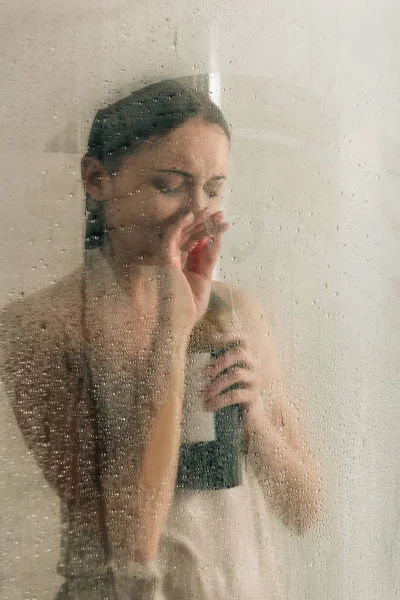 Mujer deprimida solitaria en la ducha con botella de vino en casa - foto de stock