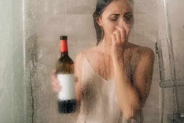 Femme déprimée solitaire sous la douche avec bouteille de vin à la maison — Photo de stock