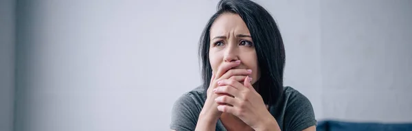 Panoramic shot of depressed brunette woman covering mouth at home with copy space — Stock Photo