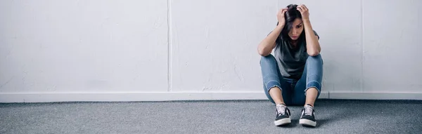 Panoramaaufnahme einer deprimierten brünetten Frau, die zu Hause mit Kopierraum auf dem Boden sitzt — Stockfoto