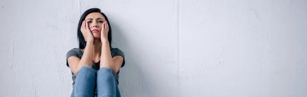 Panoramic shot of depressed brunette woman sitting on floor at home — Stock Photo