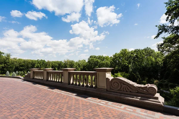 Clôture en béton blanc près des arbres verts contre le ciel bleu — Photo de stock