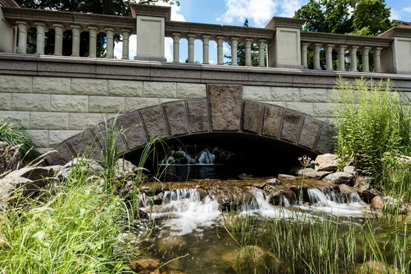Ponte di pietra vicino al vapore con acqua che scorre su rocce nel parco — Foto stock
