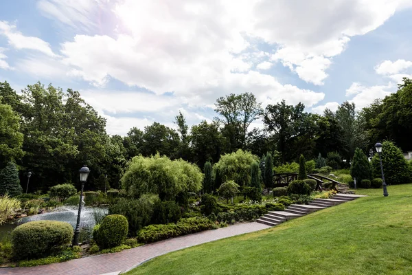 Street lamps near walkway and bushes in park with fountain — Stock Photo