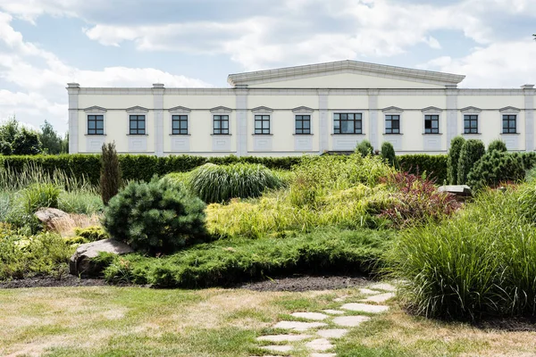 White house near green trees and bushes against blue sky with clouds — Stock Photo