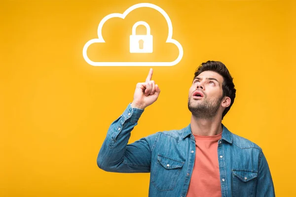 Confused handsome man pointing with finger at internet security icons isolated on yellow — Stock Photo