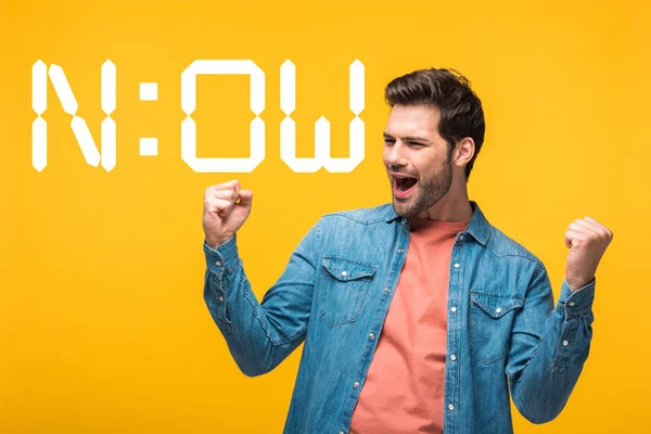 Happy handsome man showing yes gesture isolated on yellow near now lettering — Stock Photo
