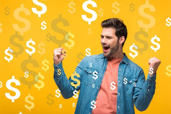Happy handsome man showing yes gesture isolated on yellow with dollars icons — Stock Photo