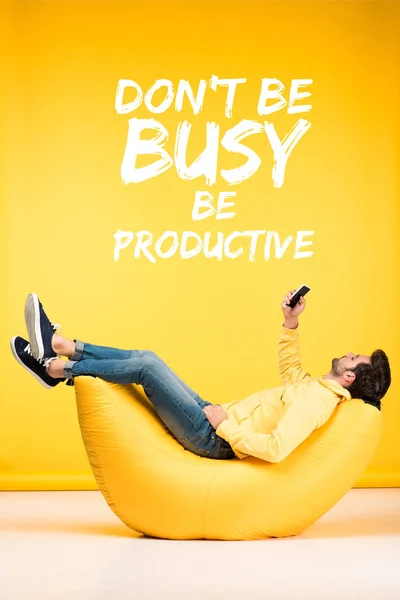 Hombre relajante en silla de la bolsa de frijol y el uso de teléfono inteligente sobre fondo amarillo con no estar ocupado, ser ilustración productiva — Stock Photo