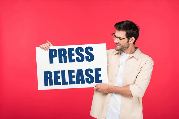 Handsome man holding white placard with press release illustration isolated on red — Stock Photo