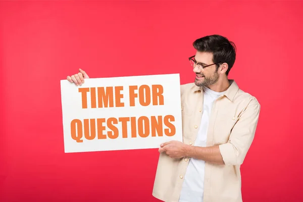 Hombre guapo sosteniendo pancarta blanca con tiempo para preguntas ilustración aislado en rojo - foto de stock