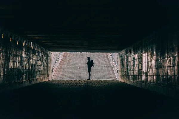 Side view of young adult man with backpack in tunnel — Stock Photo