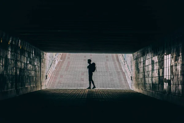 Side view of young adult man with backpack in tunnel — Stock Photo