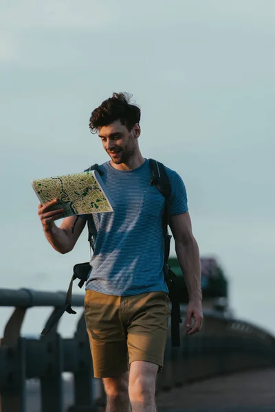 Homem bonito em t-shirt e shorts olhando para o mapa — Fotografia de Stock