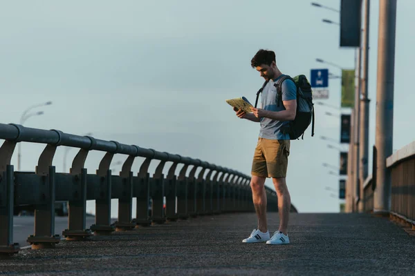 Handsome man in t-shirt and shorts looking at map — Stock Photo