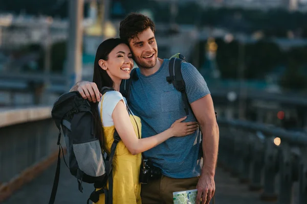 Handsome man and asian woman hugging and looking away — Stock Photo