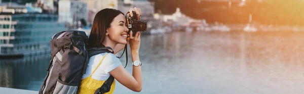 Vista laterale della donna asiatica con zaino scattare foto — Foto stock
