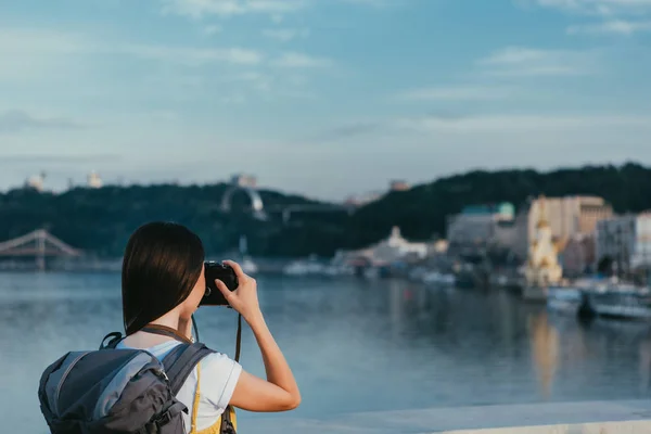 Back view of brunette woman with backpack taking photo — Stock Photo