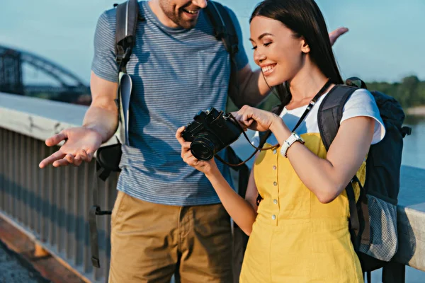 Cropped view of man and asian woman in overalls looking at digital camera — Stock Photo