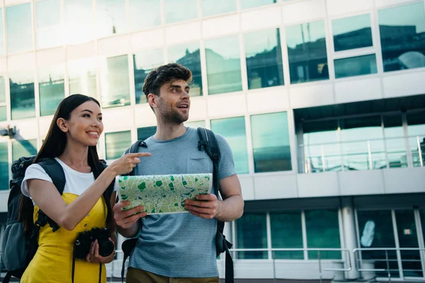 Handsome man holding map and asian woman pointing with finger — Stock Photo