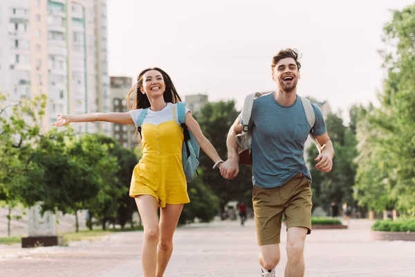 Handsome man and asian woman running and looking away — Stock Photo
