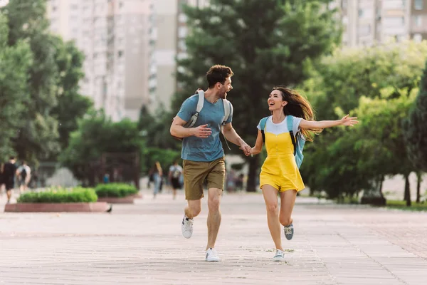 Guapo hombre y asiático mujer corriendo y mirando el uno al otro - foto de stock