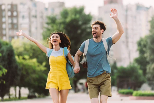 Schöner Mann und asiatische Frau läuft und winkt außerhalb — Stockfoto