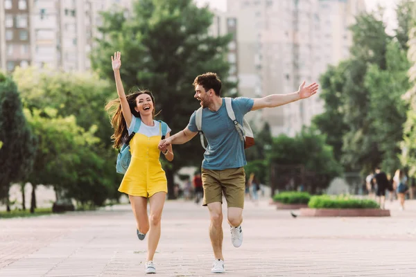 Handsome man and asian woman running with outstretched hands — Stock Photo