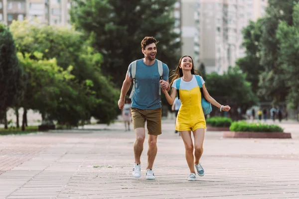 Handsome man and asian woman running and looking away — Stock Photo