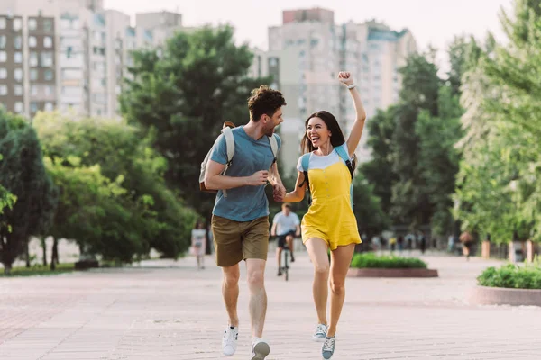 Guapo hombre y asiático mujer corriendo y mostrando sí gesto - foto de stock