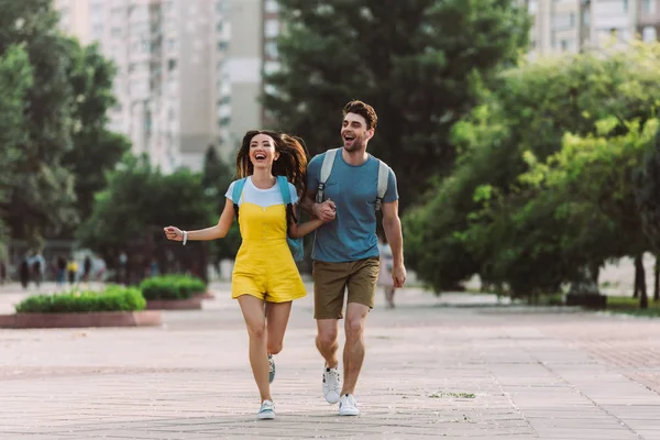 Handsome man and asian woman running and looking away — Stock Photo