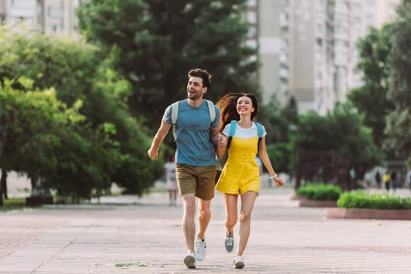 Handsome man and asian woman running and looking away — Stock Photo