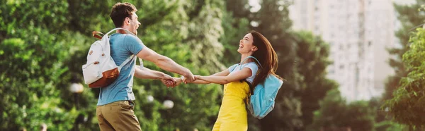 Panoramic shot of man and asian woman smiling and holding hands — Stock Photo