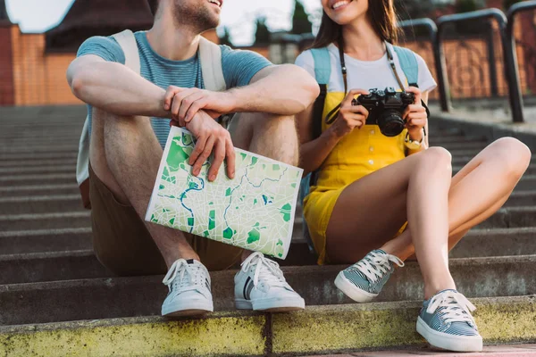 Cropped view of woman holding digital camera and handsome man holding map — Stock Photo