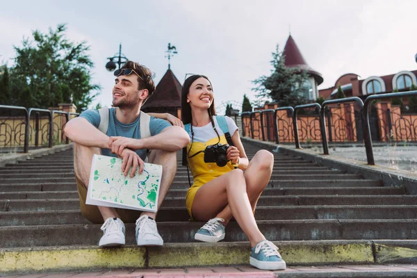 Sorridente e asiatico donna guardando lontano e bello uomo holding mappa — Foto stock