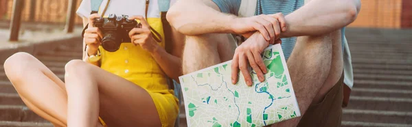 Tiro panorâmico de mulher segurando câmera digital e homem segurando mapa — Fotografia de Stock