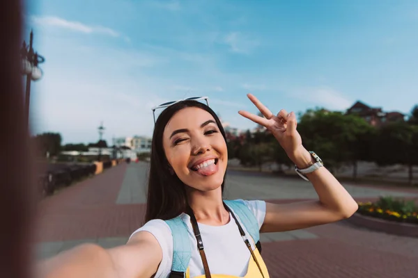 Attraente e asiatico donna presa selfie e bastone fuori lingua — Foto stock