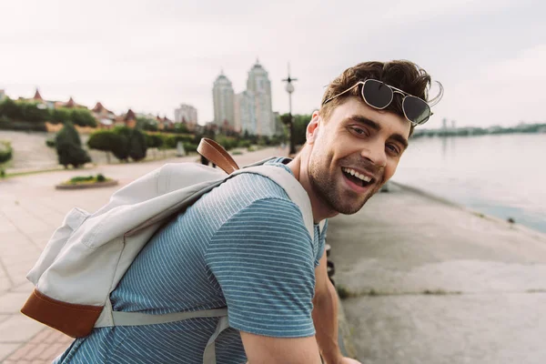 Homem bonito em t-shirt com óculos sorrindo e olhando para a câmera — Fotografia de Stock