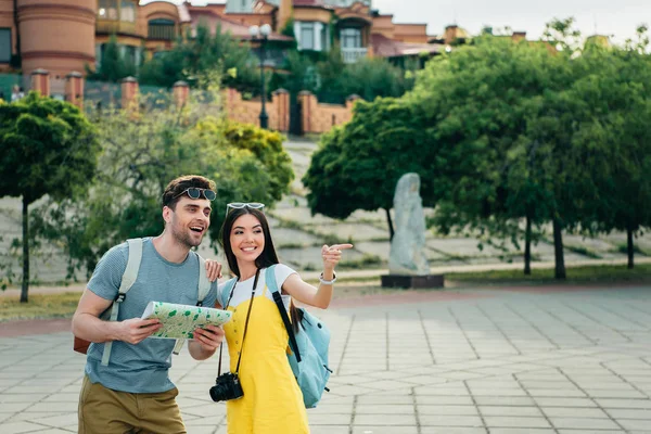Schöner Mann mit Karte und asiatische Frau, die mit dem Finger zeigt — Stockfoto