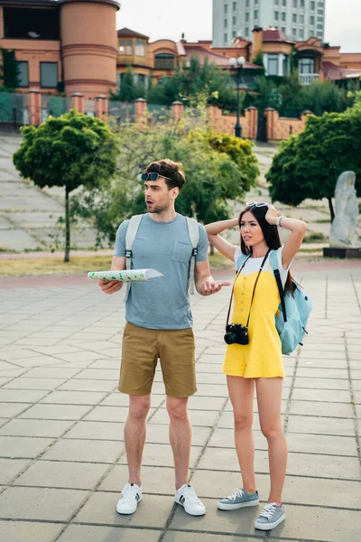 Сумний і красивий чоловік тримає карту і азіатська жінка дивиться далеко — стокове фото