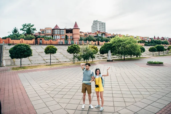 Sad and handsome man holding map and asian woman looking away — Stock Photo