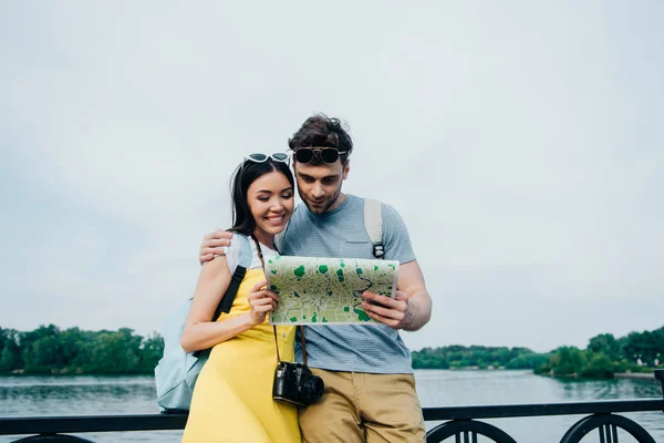 Bel homme et asiatique femme câlin et regarder carte — Photo de stock